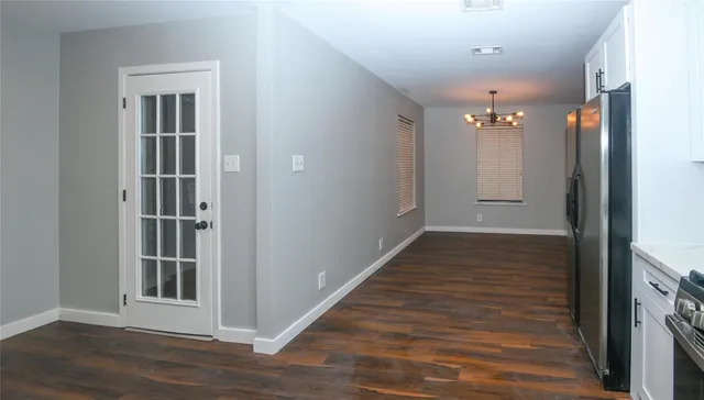 a view of a hallway with wooden floor and cabinet