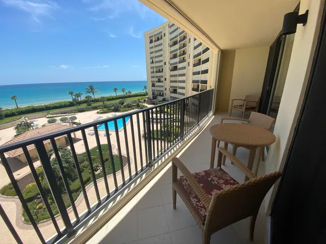 a view of a swimming pool with lawn chairs and potted plants