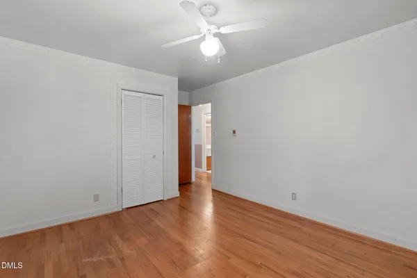 an empty room with wooden floor and fan