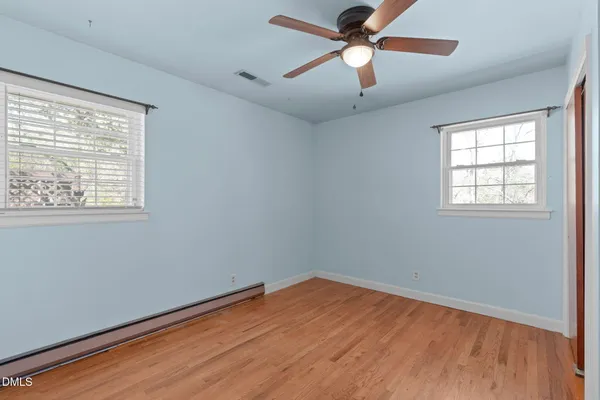 a view of empty room with wooden floor and fan