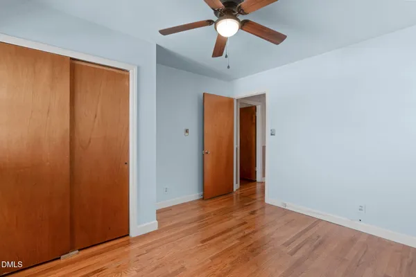 an empty room with wooden floor closet and windows