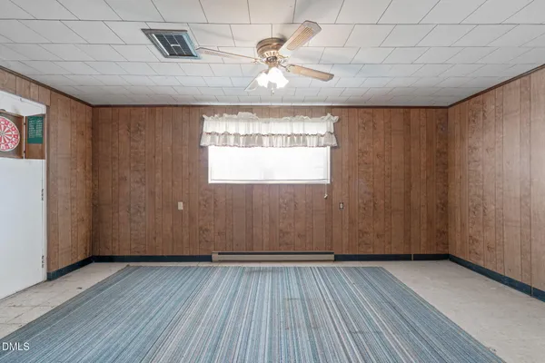 an empty room with wooden floor chandelier fan and windows