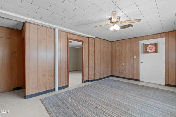 a view of an empty room with wooden floor and a ceiling fan