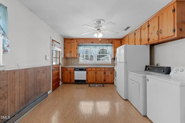 a kitchen with stainless steel appliances a refrigerator a sink dishwasher a stove and white cabinets with wooden floor