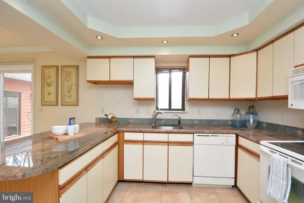 a kitchen with stainless steel appliances granite countertop a sink dishwasher a stove a refrigerator with a dining table and chairs