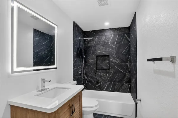a bathroom with a sink toilet vanity and shower