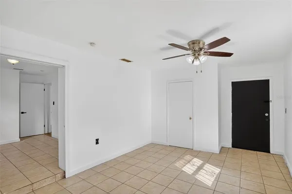 a view of an empty room with chandelier fan