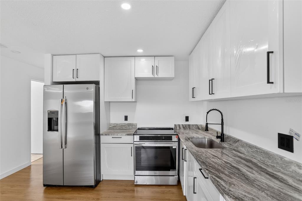 101 West Celeste Street Apopka, FL 32703 - Photo 8 of 47 a kitchen with stainless steel appliances granite countertop a refrigerator a sink a stove and white cabinets with wooden floor