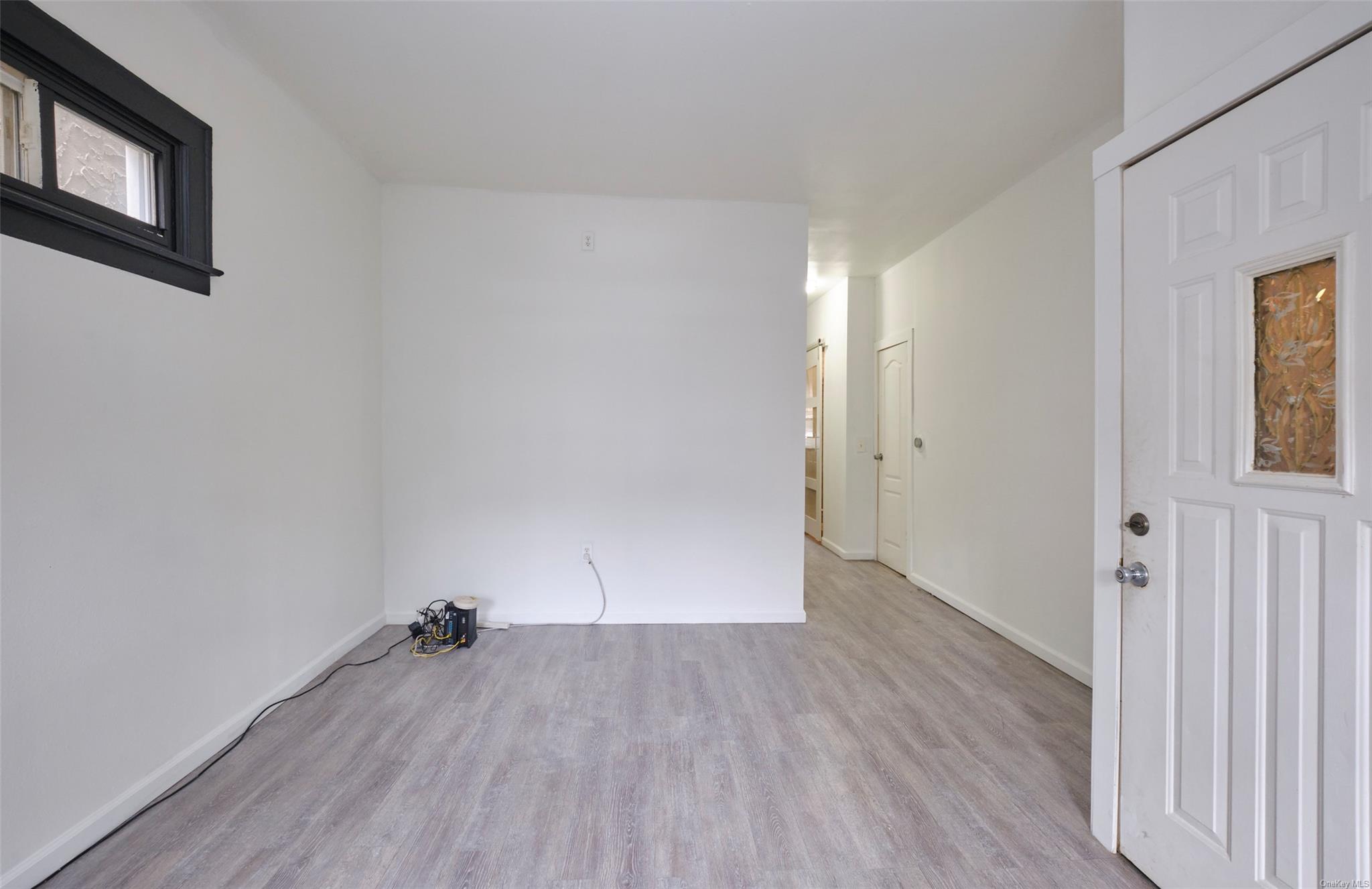 80-19 86th Road Queens, NY 11421 - Photo 4 of 26 an empty room with wooden floor and windows