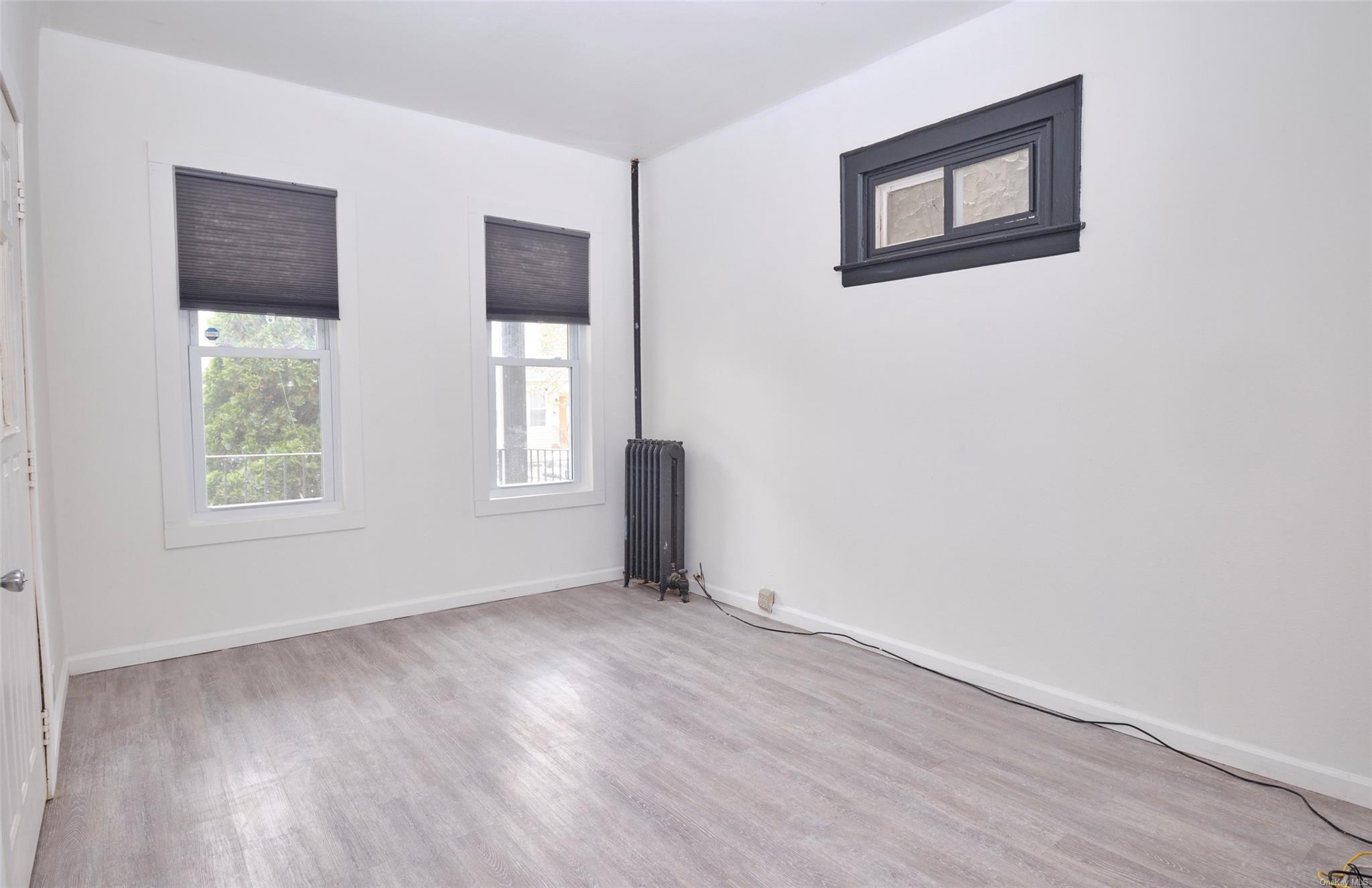 80-19 86th Road Queens, NY 11421 - Photo 5 of 26 a view of an empty room with wooden floor and a window