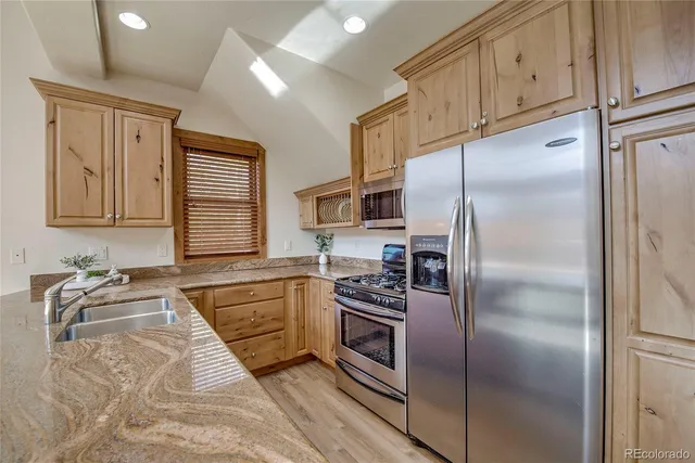 a kitchen with granite countertop stainless steel appliances a refrigerator stove top oven and sink