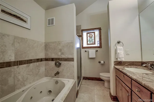 a bathroom with a granite countertop sink a toilet and shower