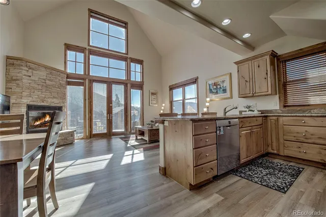 a kitchen with stainless steel appliances kitchen island granite countertop a stove top oven a sink a dining table and chairs with wooden floor