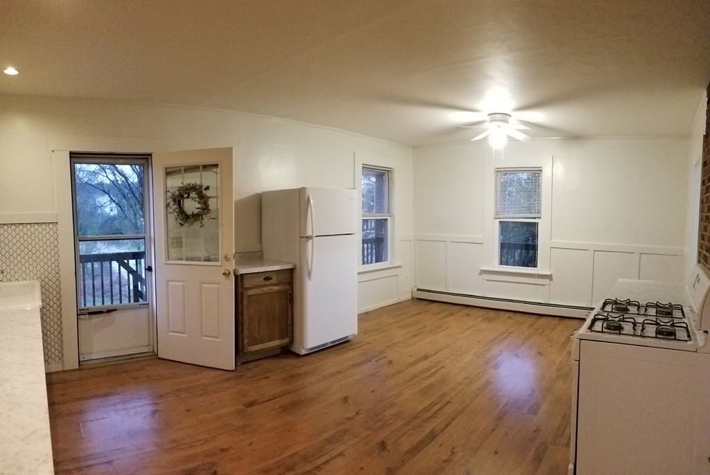 a view of a kitchen with refrigerator and wooden floor