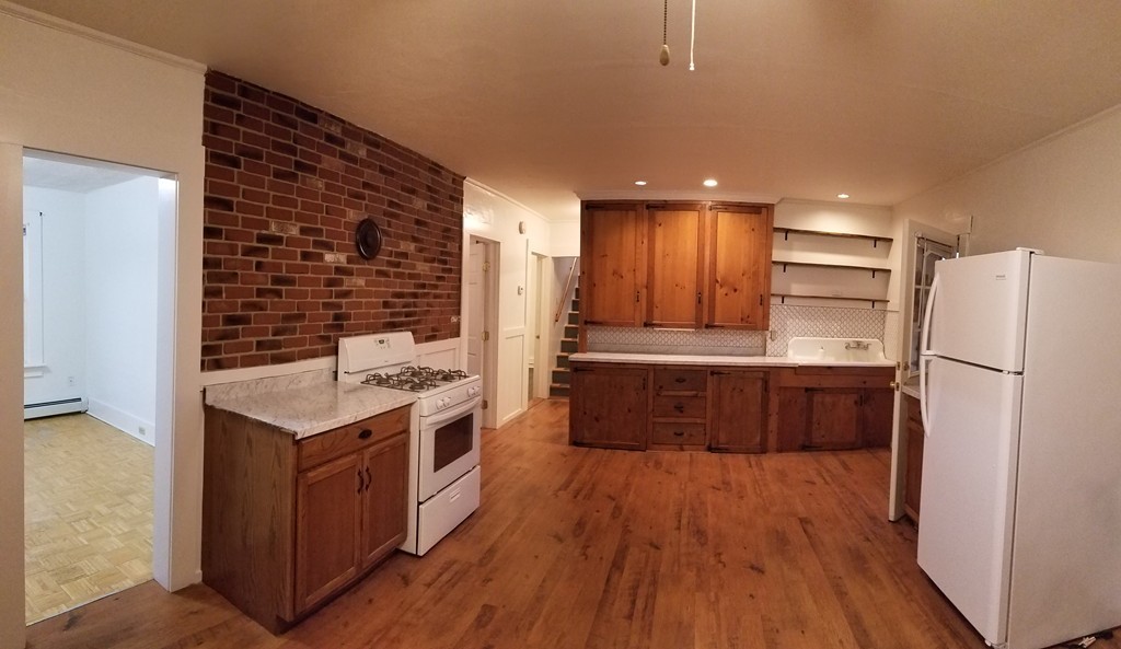 63 Harrington Street, Unit 2 Southbridge, MA 01550 - Photo 3 of 15 a kitchen with a wooden floor and a refrigerator