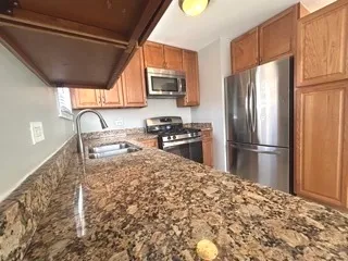 a kitchen with granite countertop a refrigerator and a stove top oven