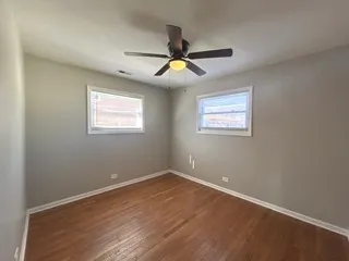a view of an empty room with window and chandelier fan