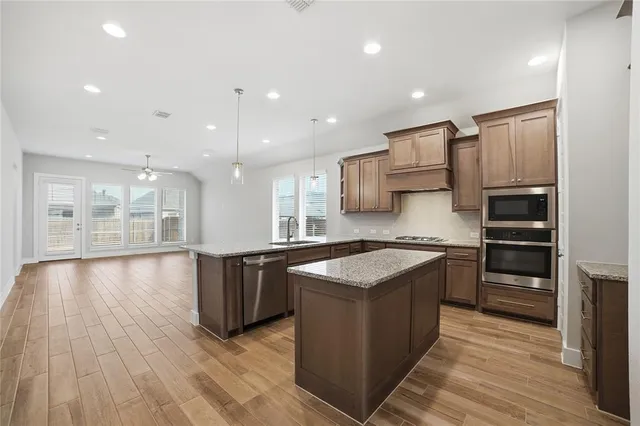 a kitchen with stainless steel appliances granite countertop a stove a sink and a refrigerator