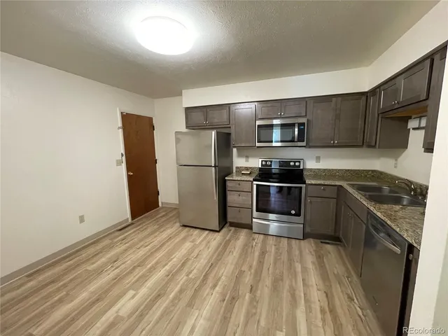 a kitchen with granite countertop a refrigerator and a stove top oven