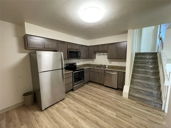 a kitchen with cabinets stainless steel appliances and wooden floor