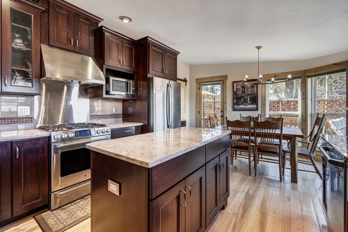 379 Hummingbird Circle Silverthorne, CO 80498 - Photo 6 of 44 a kitchen with stainless steel appliances granite countertop a stove a refrigerator a kitchen island a dining table and chairs with wooden floor