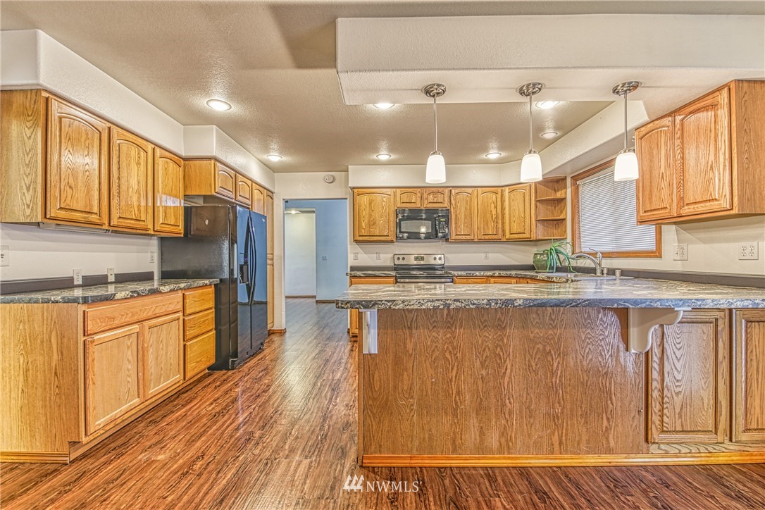 18212 Empire Street Southwest Rochester, WA 98579 - Photo 12 of 29 a kitchen with stainless steel appliances granite countertop a refrigerator a sink dishwasher a stove and white countertops with wooden floor