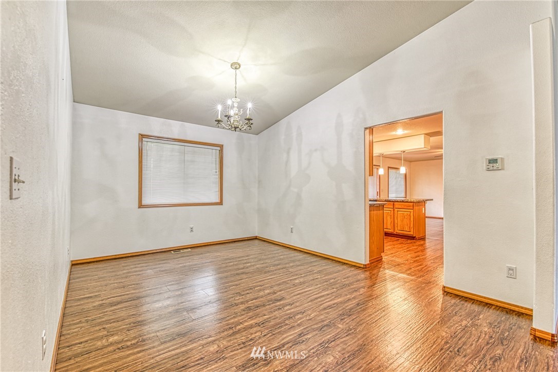 18212 Empire Street Southwest Rochester, WA 98579 - Photo 29 of 29 an empty room with wooden floor chandelier and windows