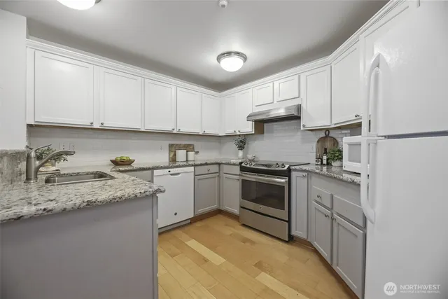 a kitchen with granite countertop a sink stainless steel appliances and cabinets