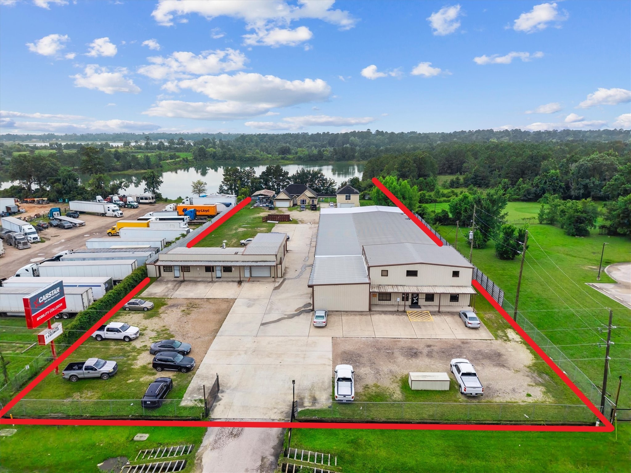 11066 Sh 242 Conroe, TX 77385 - Photo 3 of 21 This property includes a spacious commercial building with ample parking, situated within a fenced area. It's located near a scenic lake, surrounded by greenery, offering a balance of nature and functionality.