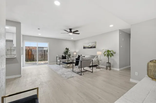 a living room with furniture and potted plants with wooden floor