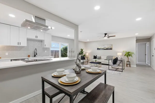 a open kitchen with stainless steel appliances granite countertop a stove a sink dishwasher a dining table and chairs with wooden floor