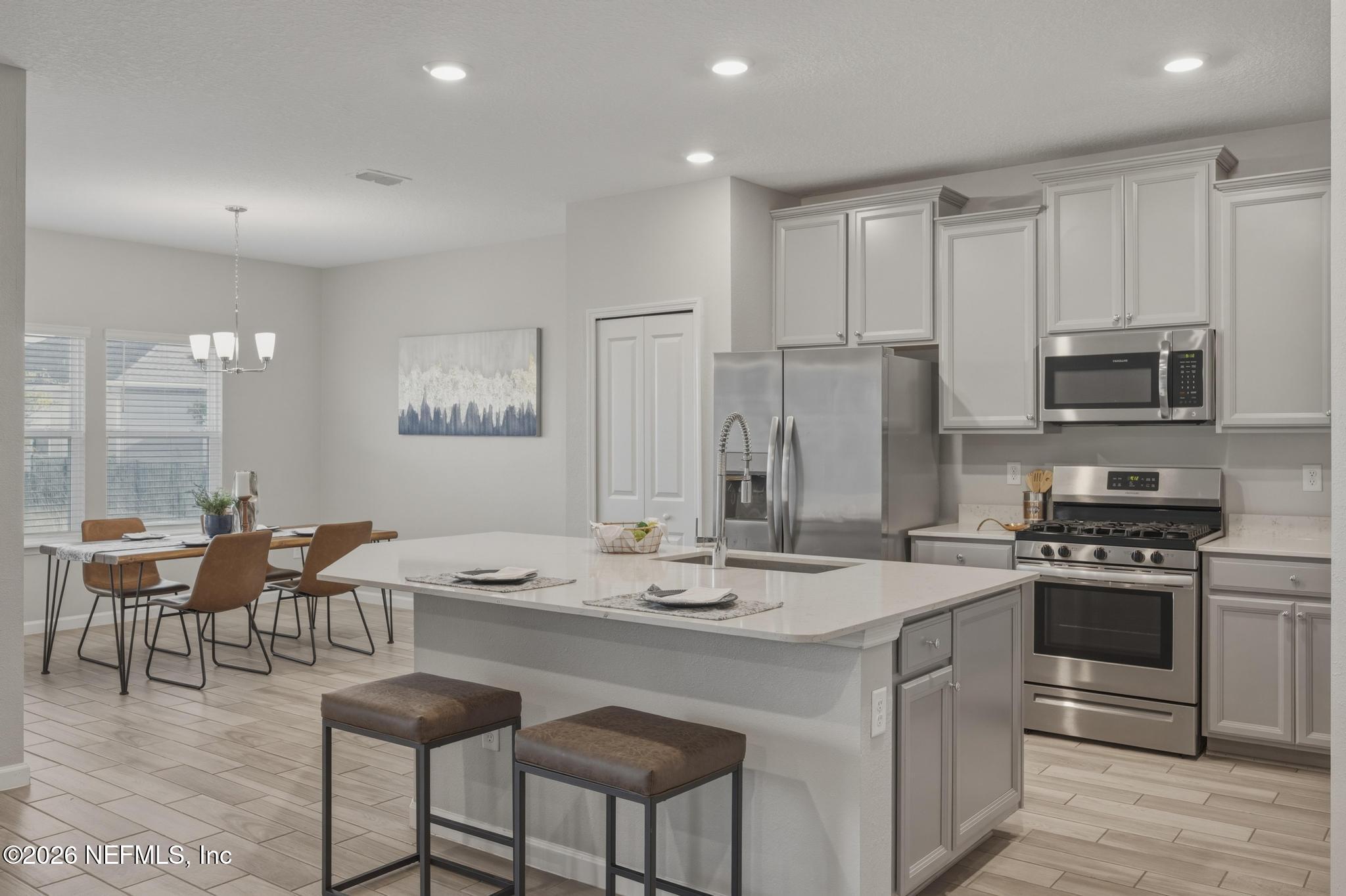 3841 Heatherbrook Place Middleburg, FL 32068 - Photo 12 of 39 a kitchen with stainless steel appliances kitchen island granite countertop a stove a sink a dining table and chairs