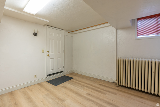 33 North 200 East Logan, UT 84321 - Photo 35 of 54 Finished below grade area featuring radiator heating unit, light wood-style flooring, and a textured ceiling