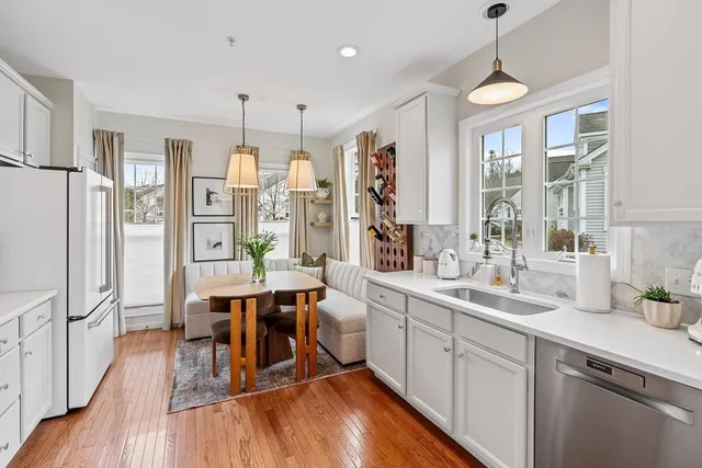 a open kitchen with stainless steel appliances granite countertop a refrigerator a sink dishwasher a dining table and chairs with wooden floor