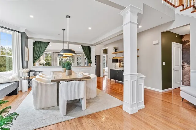 a kitchen with stainless steel appliances granite countertop a refrigerator a sink dishwasher a stove and a dining table with wooden floor