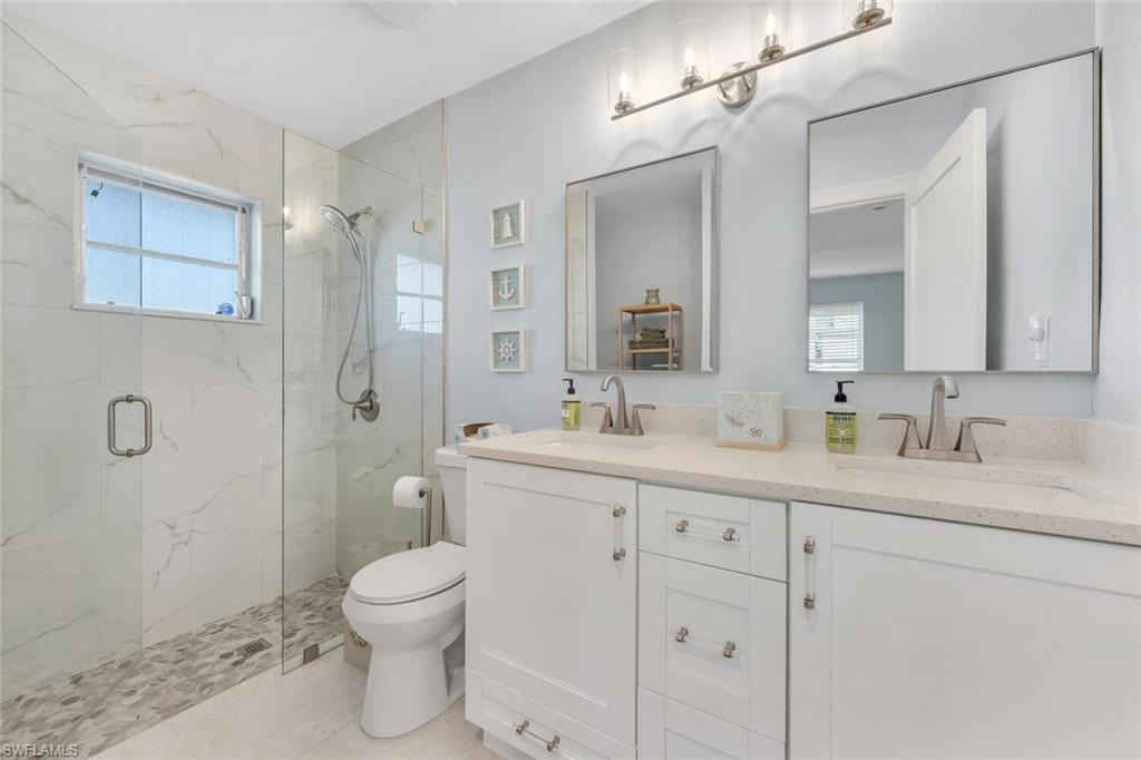385 Willet Avenue Naples, FL 34108 - Photo 11 of 19 a bathroom with a toilet a sink a mirror a shower a vanity and window