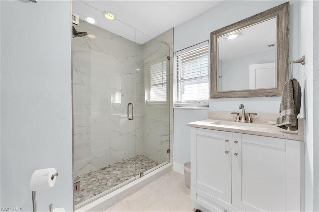 385 Willet Avenue Naples, FL 34108 - Photo 13 of 19 a bathroom with a granite countertop sink a mirror and a shower