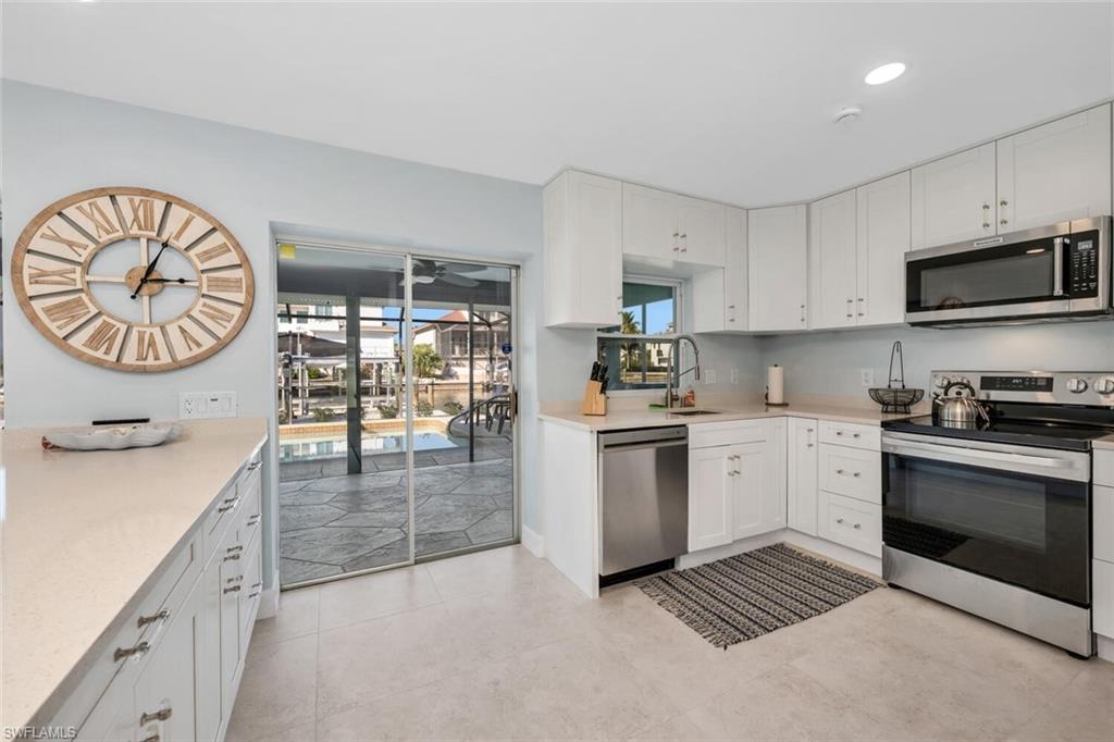 385 Willet Avenue Naples, FL 34108 - Photo 7 of 19 a kitchen with stainless steel appliances granite countertop a stove a sink and a microwave