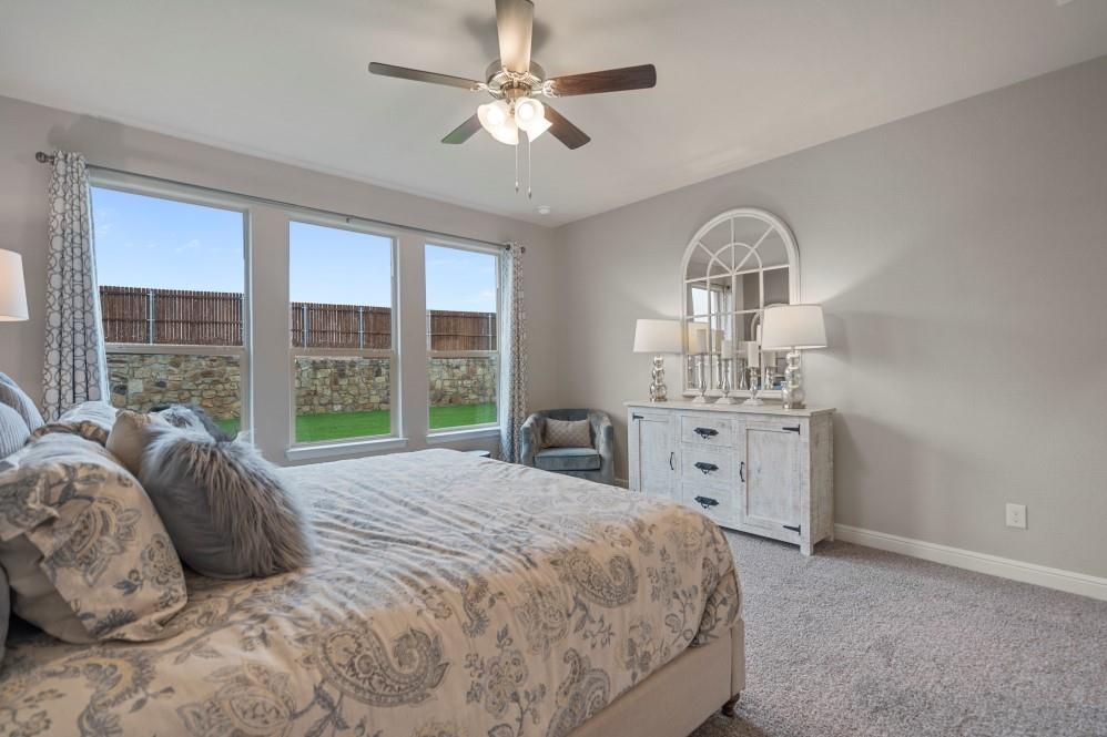 118 Stanton Avenue Rhome, TX 76078 - Photo 17 of 30 a spacious bedroom with a bed a large window and a chandelier