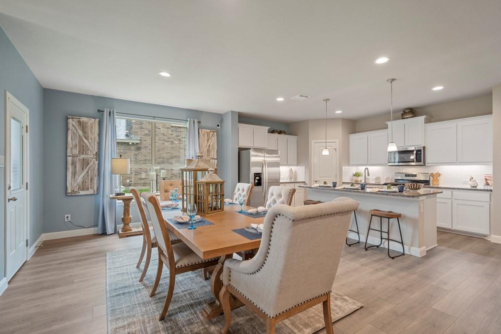 118 Stanton Avenue Rhome, TX 76078 - Photo 6 of 30 a dining room with kitchen island stainless steel appliances wooden floor table chairs and a window