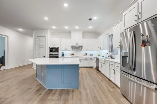 a kitchen with stainless steel appliances a sink cabinets and wooden floor
