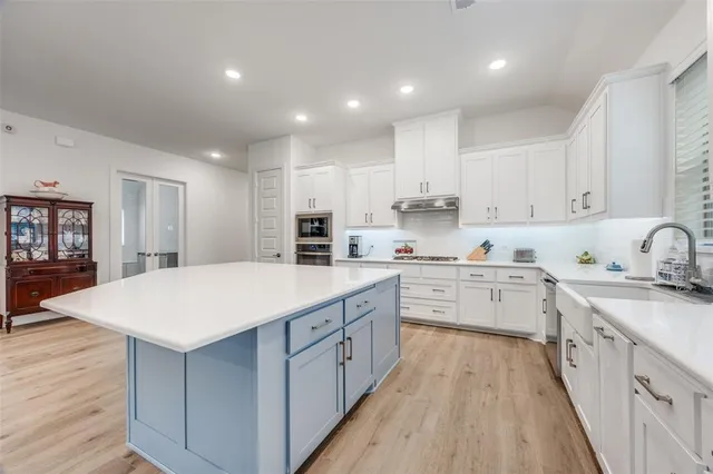 a kitchen with kitchen island sink stove and white cabinets