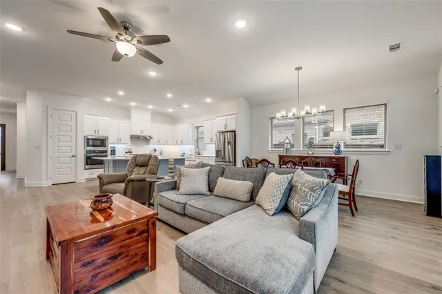 a living room with furniture kitchen view and a chandelier