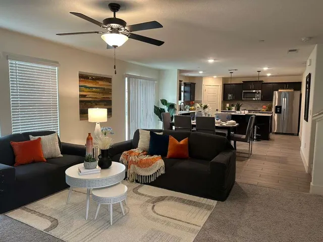 a living room with furniture kitchen view and a chandelier