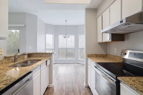 a kitchen that has a sink a stove and a wooden floor