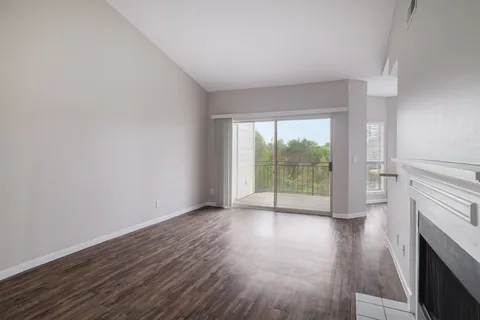 a view of empty room with wooden floor and fireplace
