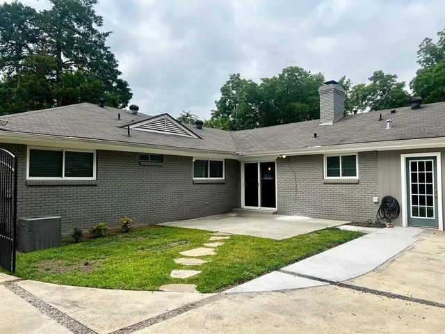 a view of a house with a yard and a large tree