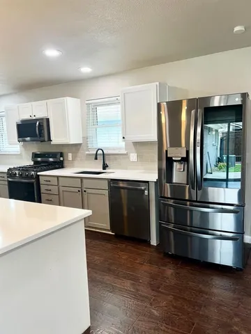 a kitchen with stainless steel appliances kitchen island granite countertop a stove a sink and a refrigerator