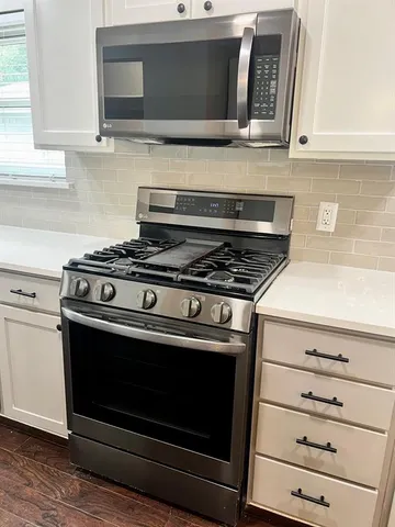 a stove top oven sitting inside of a kitchen and white cabinets