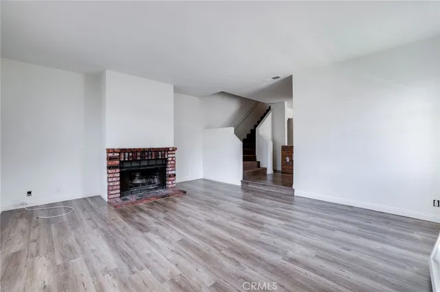 a view of empty room with wooden floor and fireplace